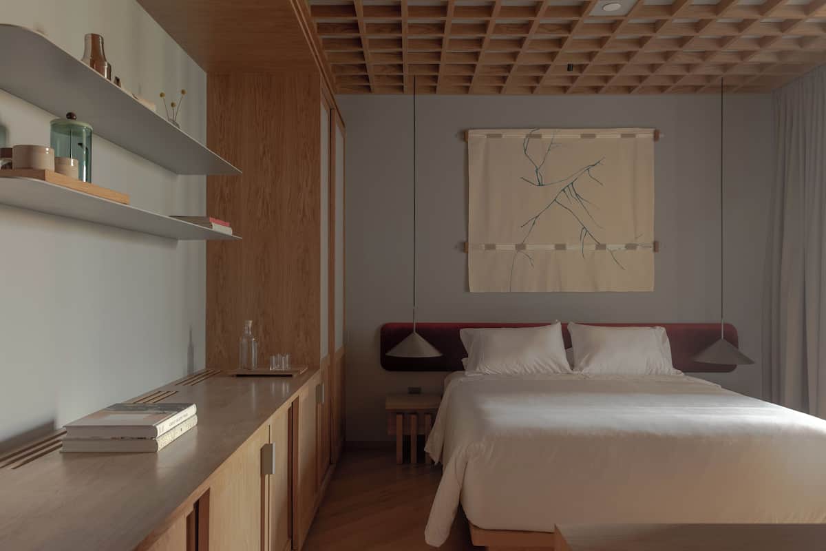 A neatly arranged bedroom with a bed, bedside tables, and a wall-mounted artwork.