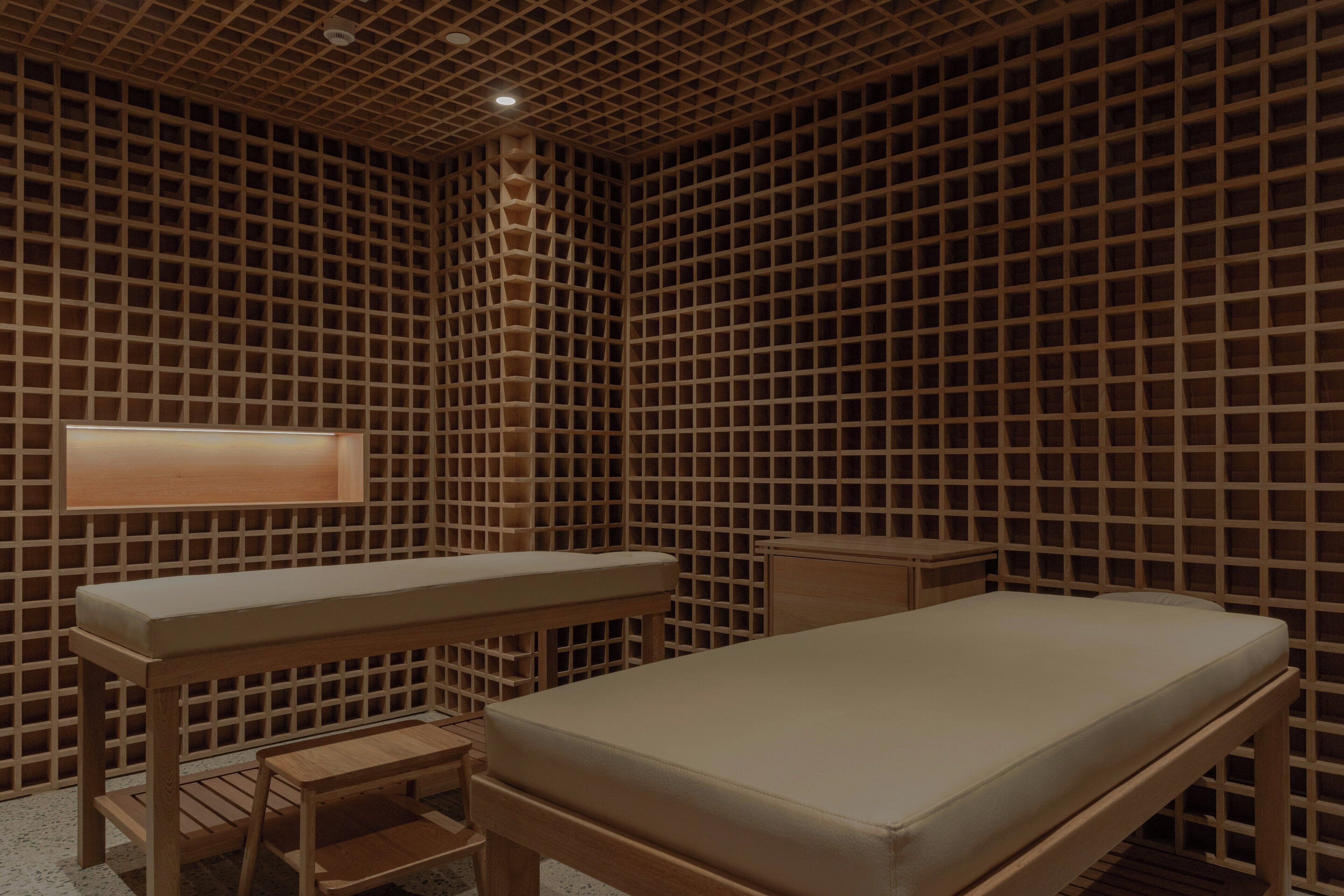 Ein Zimmer mit Holzboden, einem Bett, einem kleinen Tisch und einer Bank.