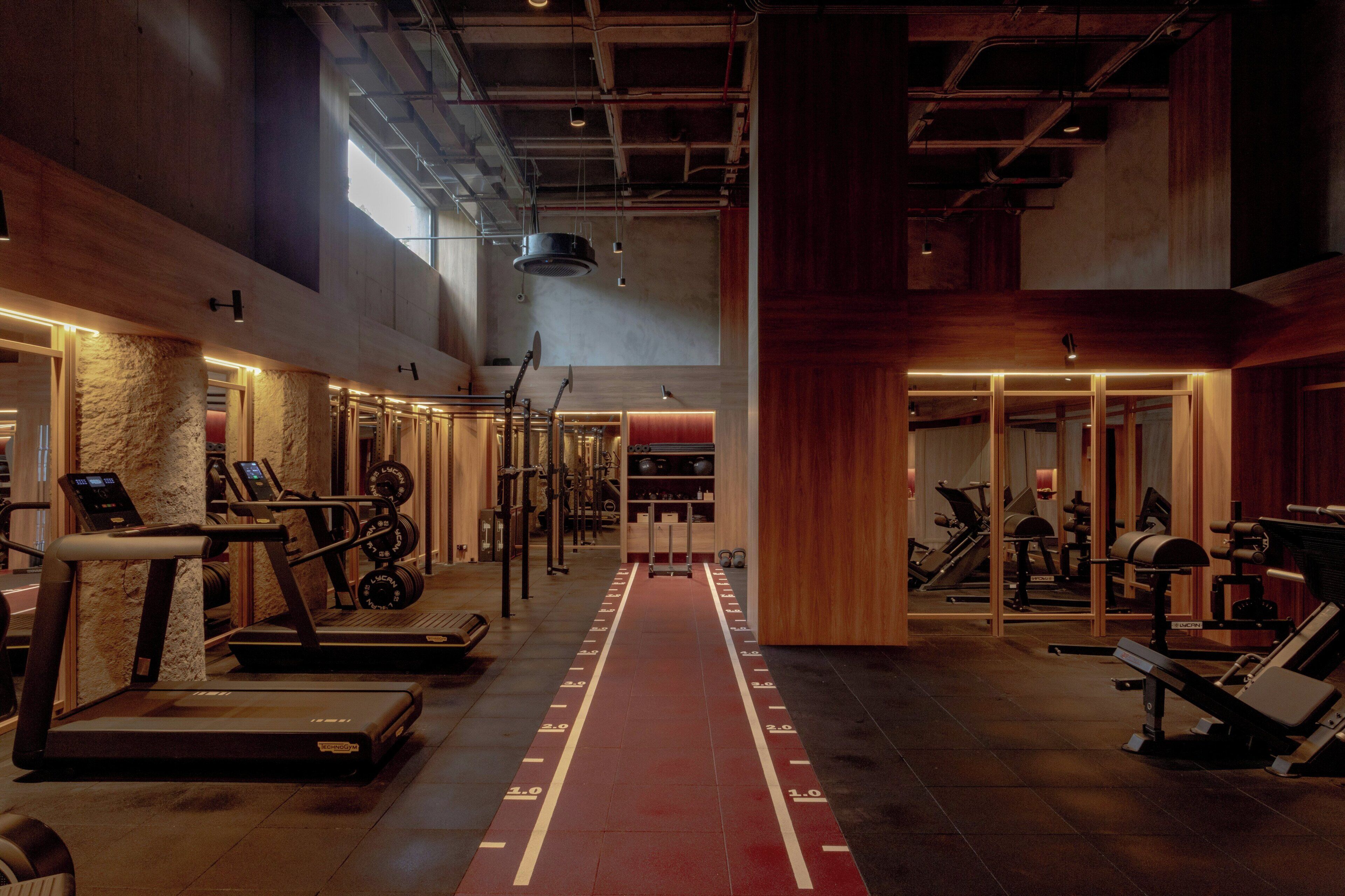 A gym with treadmills, weight machines, and a red running track.