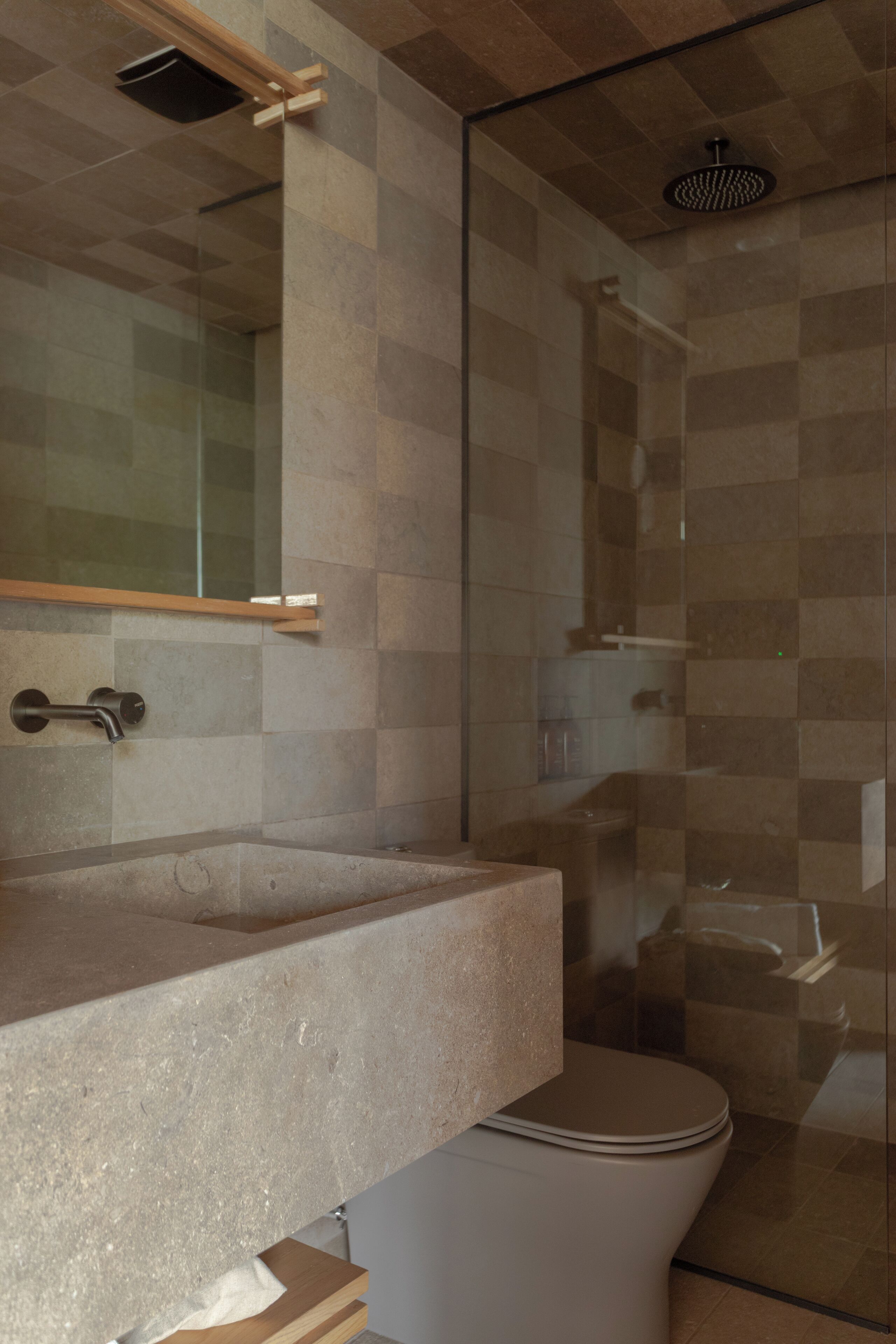 A modern bathroom with a glass shower enclosure, a built-in sink, and a toilet.