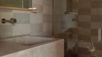 A modern bathroom with a glass shower enclosure, a built-in sink, and a toilet.