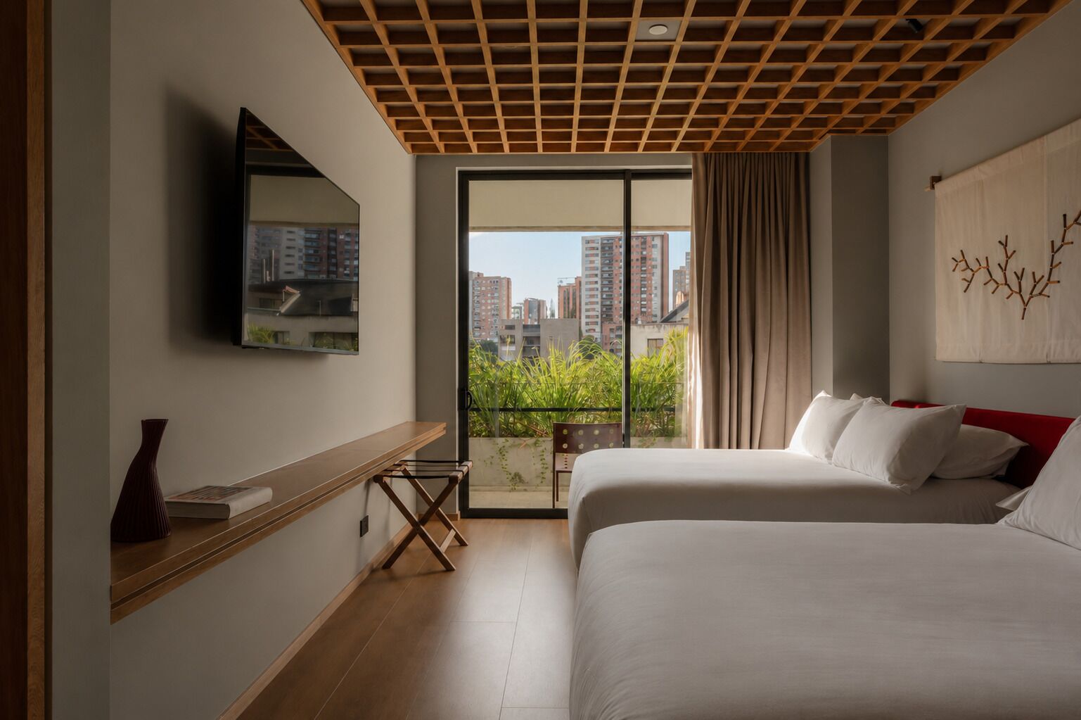 Habitación de hotel con una cama grande, una mesita de noche, un espejo y vistas a la ciudad desde un balcón.