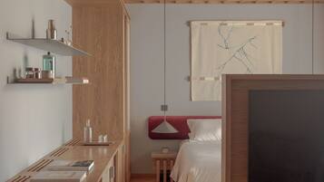 A modern room with a wooden ceiling, a bed, a TV, and a small table with books and a lamp.