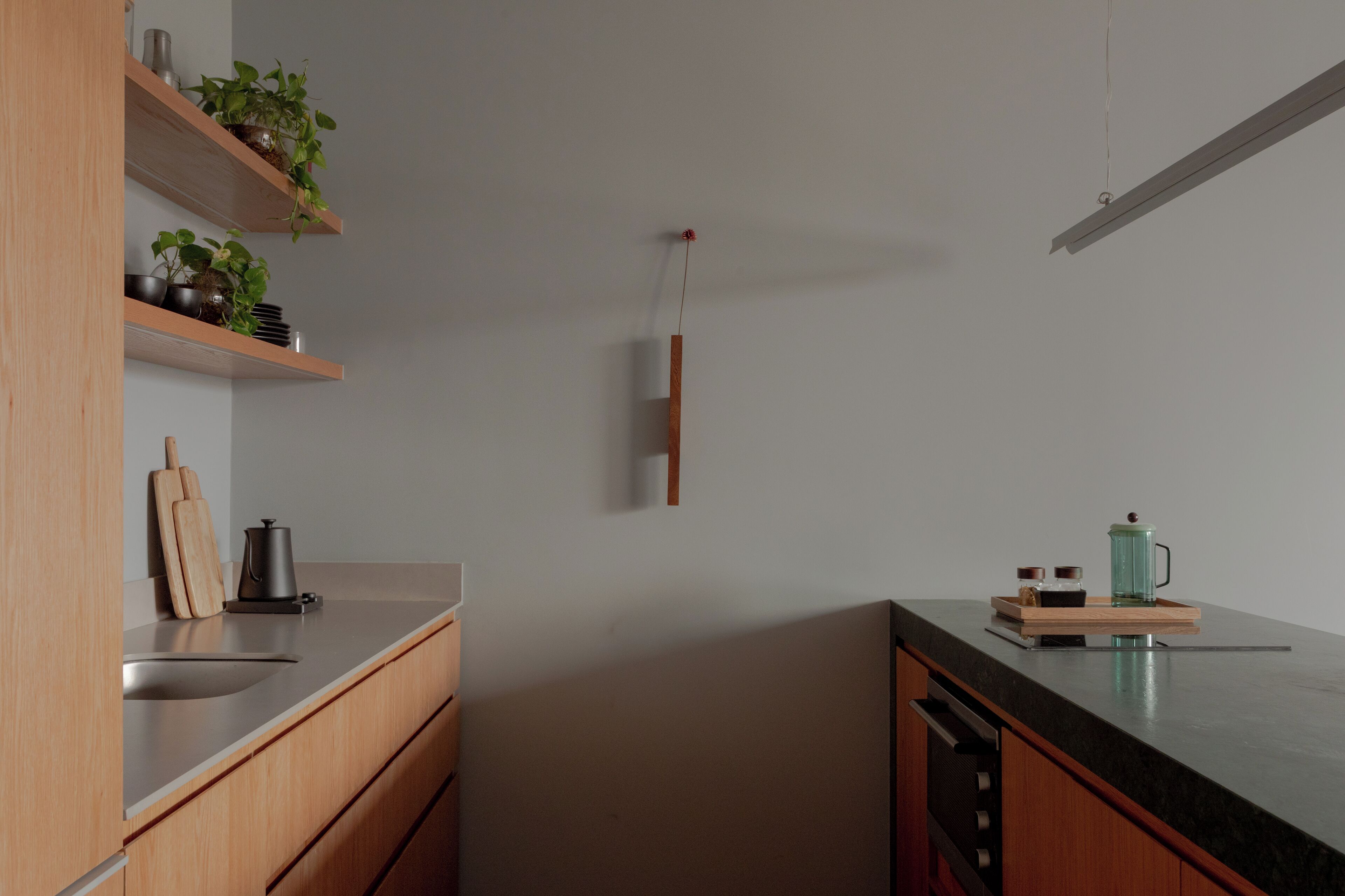 Et moderne køkken med træskabe, en sort bordplade og en hængende lampe.
