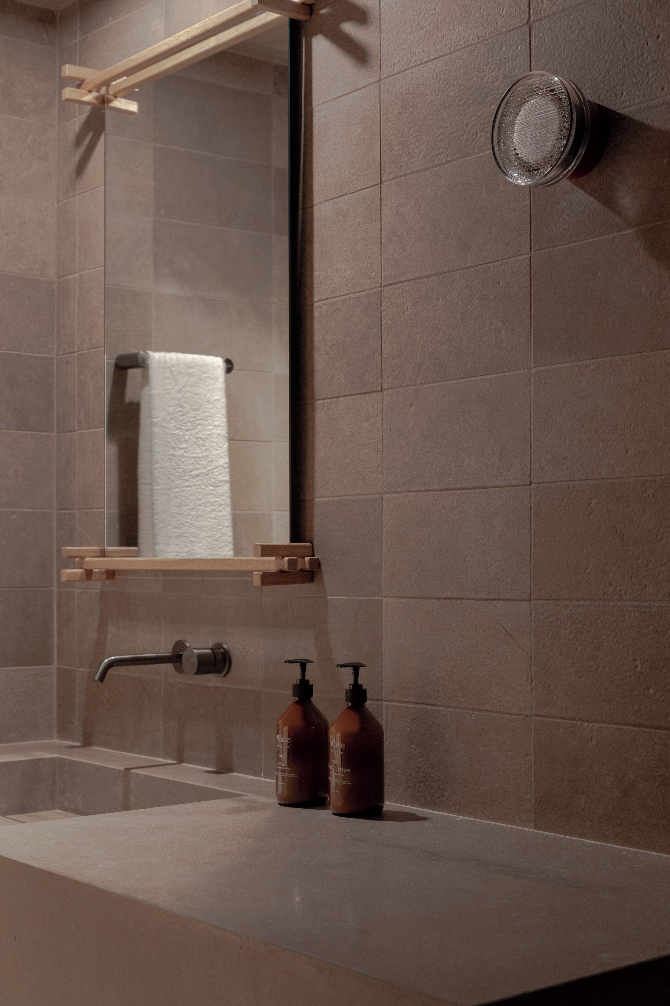 A bathroom with a large mirror, a towel rack, a sink, and two bottles of soap.