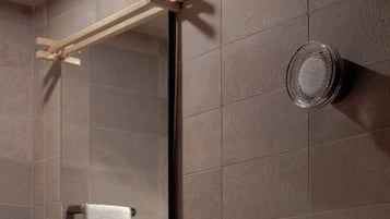 A bathroom with a large mirror, a towel rack, a sink, and two bottles of soap.