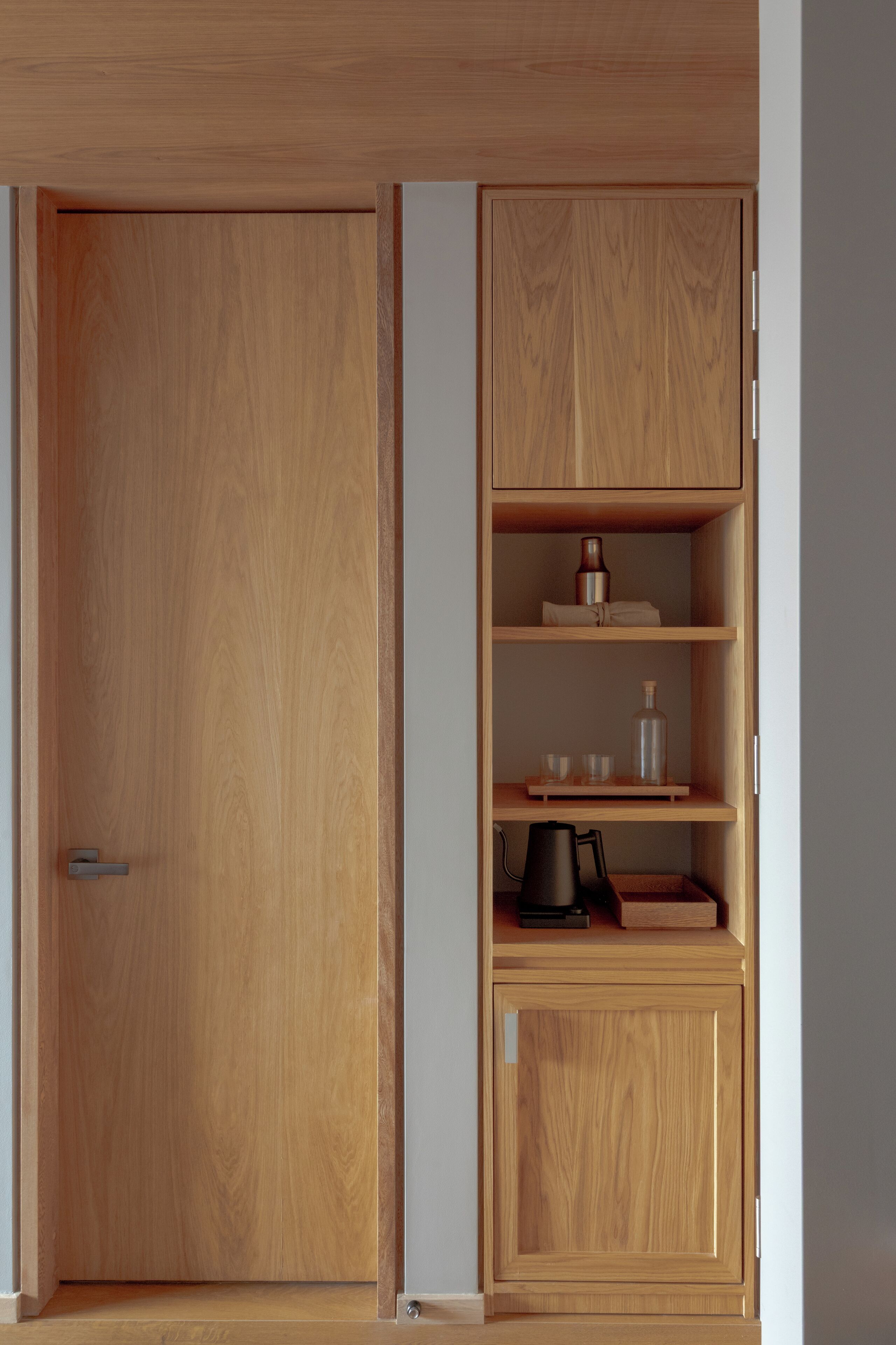 A wooden wardrobe with multiple shelves and a door.