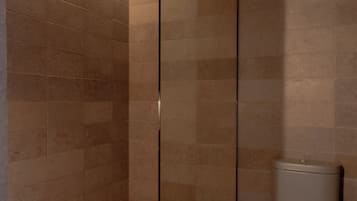 Une salle de bain moderne avec une douche à parois de verre, des toilettes et un sol carrelé.