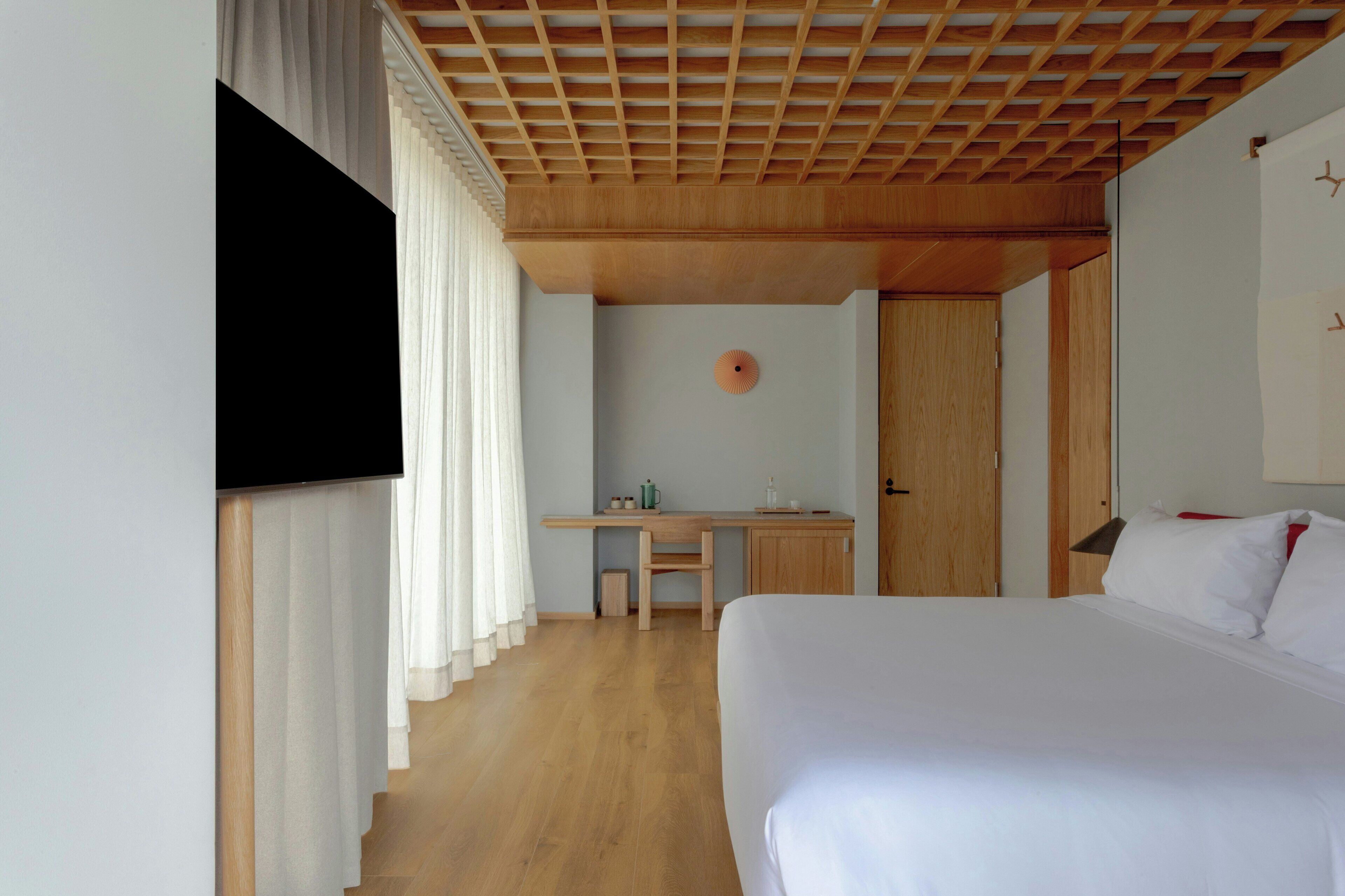 Una habitación de hotel con una cama, un escritorio, un televisor y una puerta.