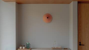 A minimalist room with a wooden desk, a chair, a cabinet, and a wall-mounted decorative item.
