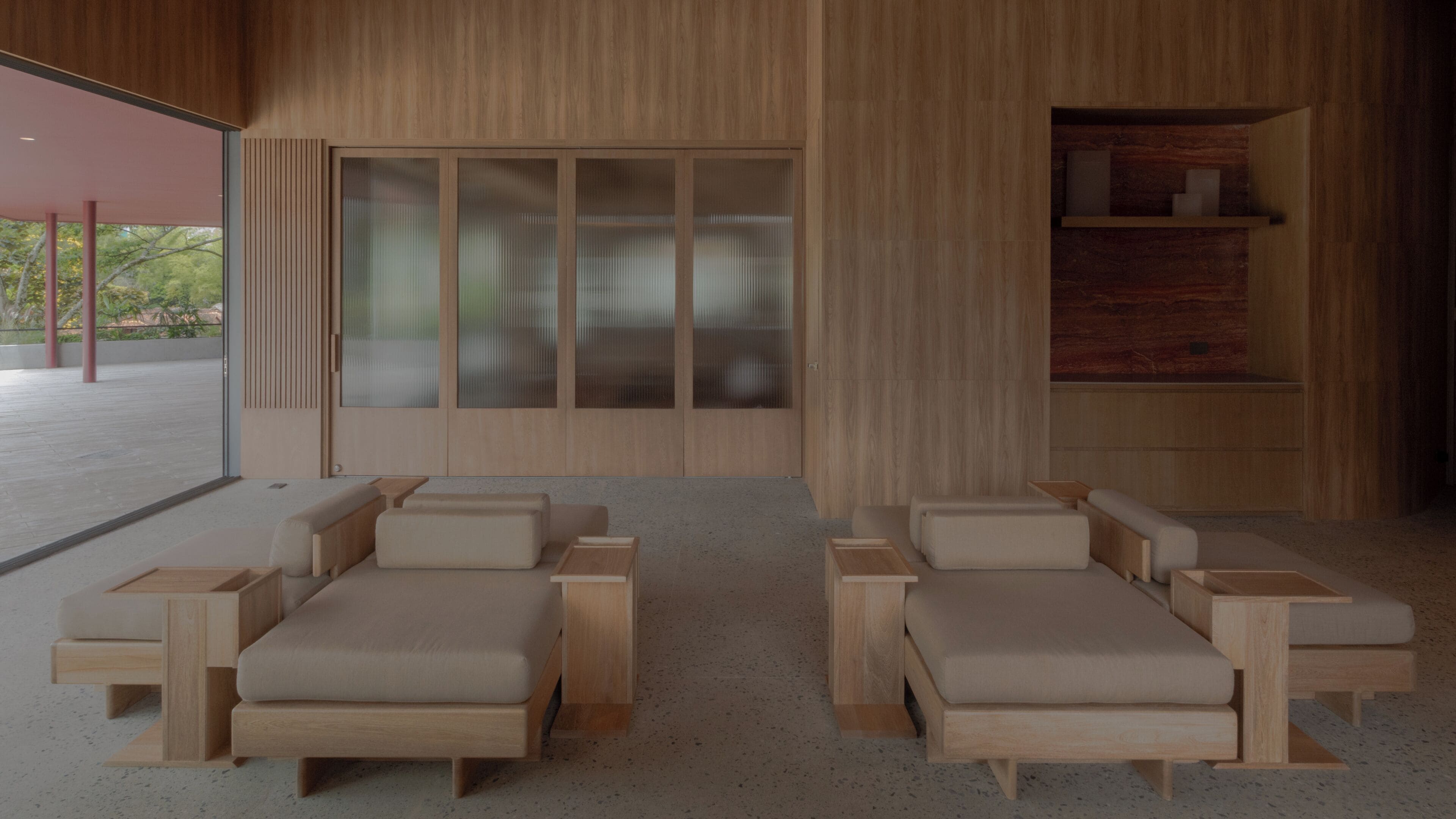 A modern interior with two wooden lounge chairs and a large sliding glass door.