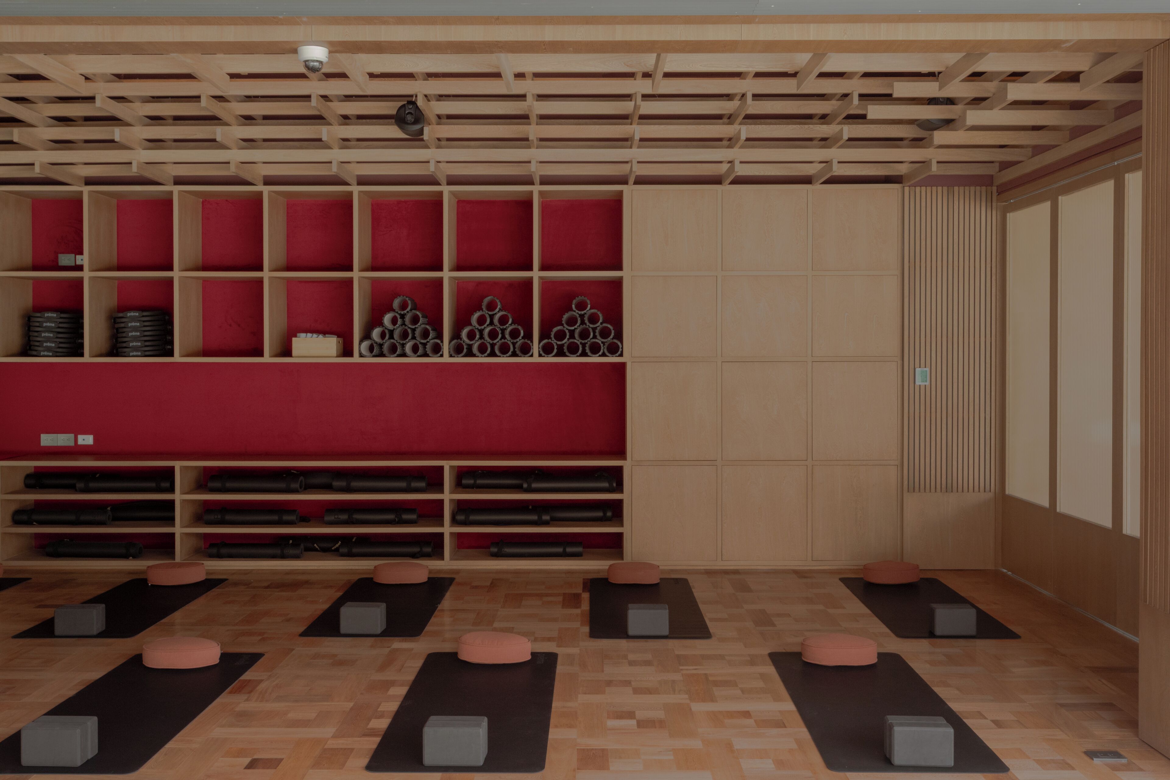 A room with a wooden ceiling, red padded shelves, and black mats on the floor.
