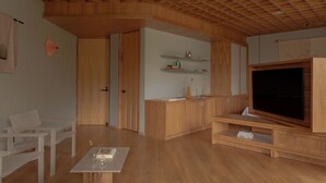 A modern living room with wooden flooring, a large flat-screen TV, and built-in wooden shelves. - Wake Medellin, a Member of Design Hotels (Medellín)