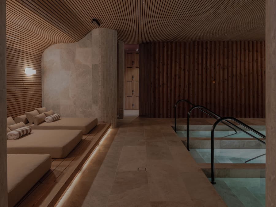 Un área de spa con una camilla de masaje, una piscina pequeña y una escalera.