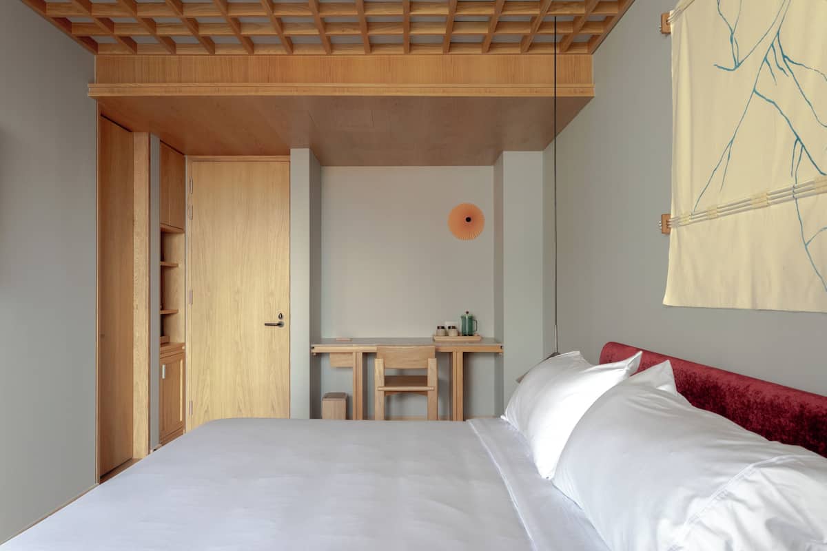 A bedroom with a bed, a desk, and a chair.