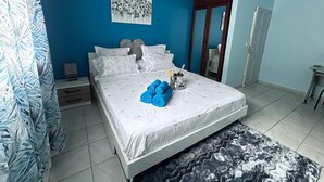 Ein Schlafzimmer mit einem Bett, einem Nachttisch, einer blauen Wand und einer Tür.