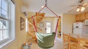 A spacious kitchen with wooden cabinets, a white refrigerator, and a hanging chair.