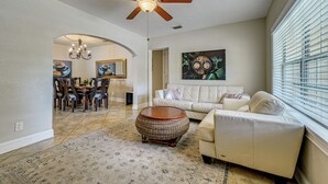 Ein Wohnzimmer mit Deckenventilator, ein Essbereich mit einer Pendelleuchte, ein Sofa und ein Couchtisch.