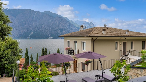 Ein Gebäude mit einem Balkon mit Blick auf einen See und Berge.