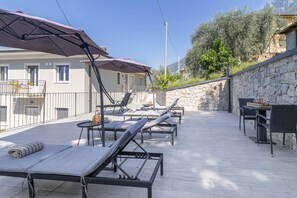 Eine Terrasse mit Liegestühlen, einem Tisch und einer Steinmauer.