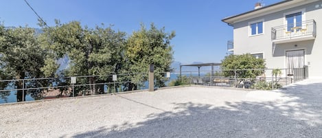 A building with a balcony, a gravel area, and trees.