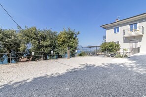 Ein Gebäude mit einem Balkon, Kiesfläche und Bäumen.