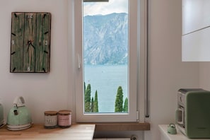 Ein Zimmer mit einer Holz-Wanduhr, einem Fenster mit Seeblick und Bergen, einem Vintage-Radio und einem Wasserkocher auf der Arbeitsplatte.