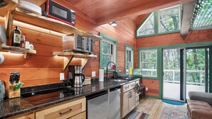 A wooden cabin kitchen with a microwave, coffee maker, and dishwasher.