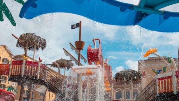 Um parque aquático com um tobogã gigante, uma área de recreação com tema de piratas e uma piscina.