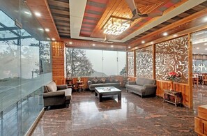 A spacious living area with a glass wall, wooden ceiling, and patterned wall panels.