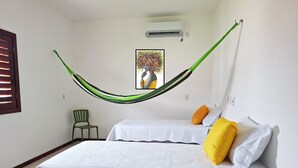 Een kamer met twee bedden, een hangmat, een stoel en een airconditioning.