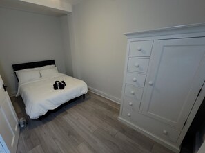 A bedroom with a bed, a white wardrobe, and a wooden floor. - Modern 2 bedroom apartament in the heart of Greenwich (London)