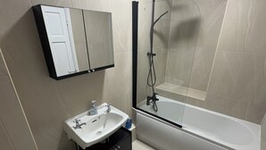 A modern bathroom with a toilet, sink, and bathtub. - Modern 2 bedroom apartament in the heart of Greenwich (London)
