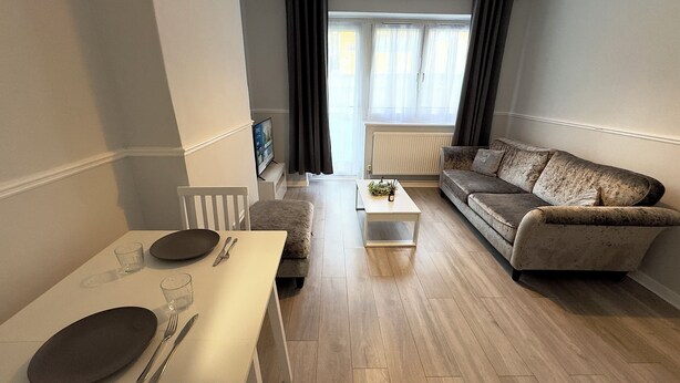 A modern living room with a white dining table, a sofa, and a coffee table. - Modern 2 bedroom apartament in the heart of Greenwich (London)