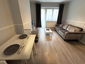 A modern living room with a white dining table, a sofa, and a coffee table. - Modern 2 bedroom apartament in the heart of Greenwich (London)