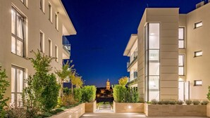 A nighttime view of a modern building with a central pathway leading to a lit-up structure resembling a church or tower. - Villa Krk - Luxury apartment by the sea with view of Krk town and shared pool (Krk (Krk))