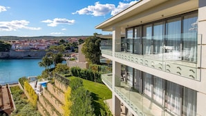 A modern building with large windows overlooking a coastal town and a body of water. - Villa Krk - Luxury apartment by the sea with view of Krk town and shared pool (Krk (Krk))