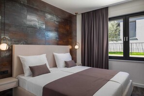 Ein Schlafzimmer mit einem großen Bett, zwei Nachttischen, einer Kopfteil und einem Fenster mit Vorhängen.