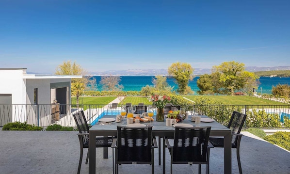 Une table à manger avec quatre chaises, une piscine et une vue sur la mer.