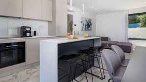 Een moderne keuken met een centraal eiland, barkrukken en een zithoek met een bank.