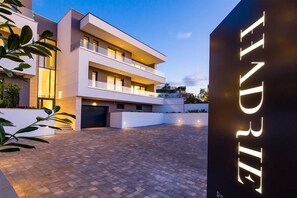 A modern multi-story building with a flat roof and a paved courtyard. - Villa Rova – Apartment with a Seaview (Malinska (Krk))