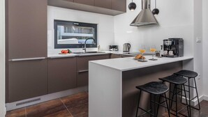 A modern kitchen with a central island, bar stools, a coffee machine, and a view of the outside. - Villa Rova – Apartment with a Seaview (Malinska (Krk))
