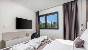 A hotel room with a bed, a desk, a flat-screen TV, and a window with curtains. - Villa Rova – Apartment with a Seaview (Malinska (Krk))