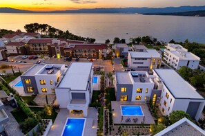 Un hôtel moderne doté de piscines sur le toit, d’un port de plaisance et offrant une vue sur la mer au coucher du soleil.