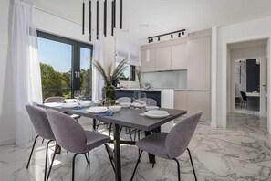 Een moderne eetruimte met een marmeren vloer, grijze stoelen en een tafel gedekt voor vier personen.