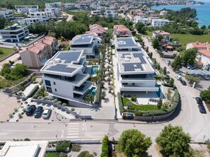 Ett modernt bostadsområde med solpaneler på taken, en swimmingpool och en välskött trädgårdsanläggning.