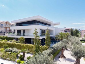 Ein modernes, zweistöckiges Haus mit flachem Dach, großen Fenstern und einem Balkon.