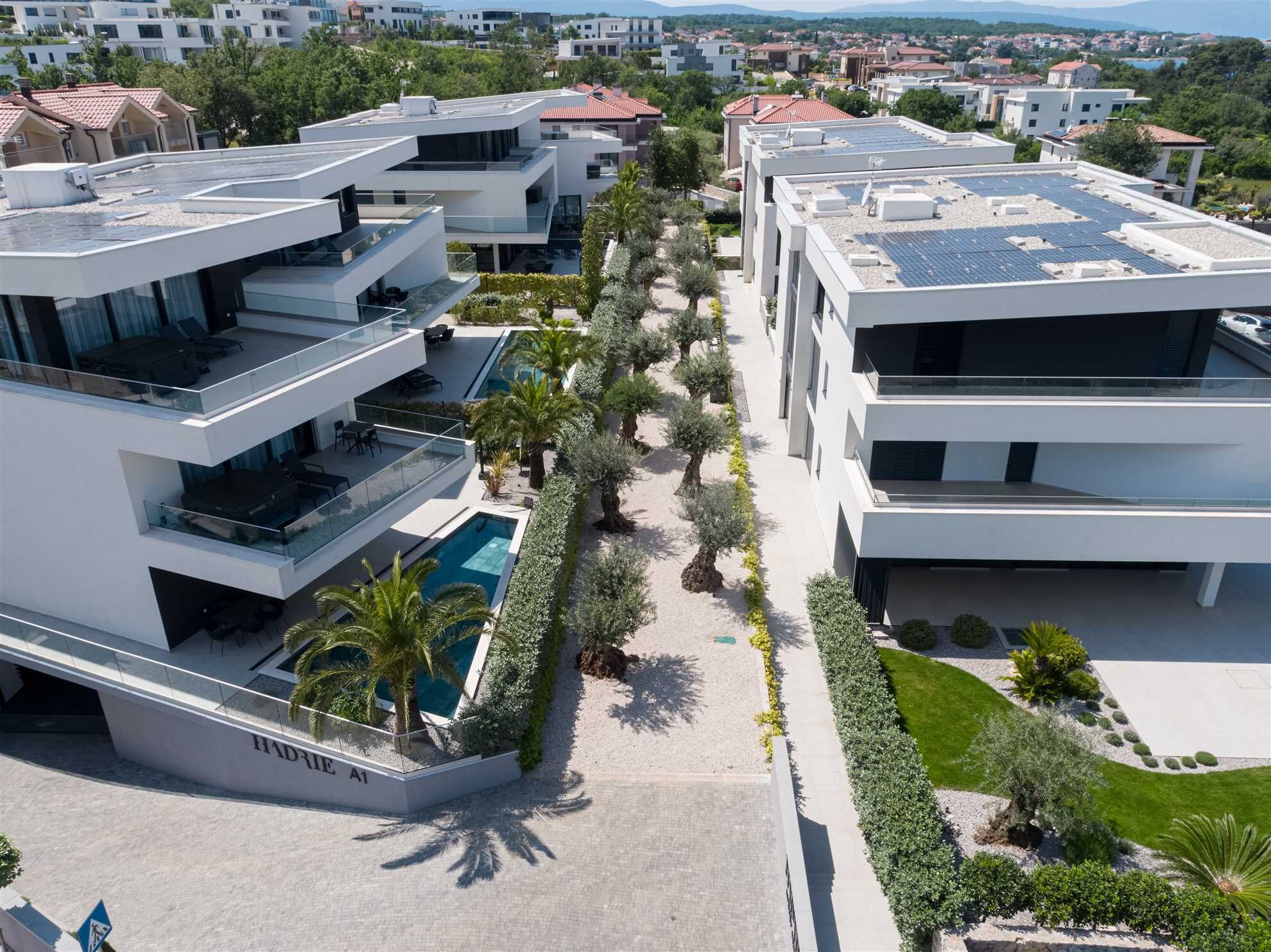 A modern residential building with a rooftop pool, solar panels, and a well-maintained garden.