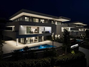 A modern multi-story house with a swimming pool, large windows, and a well-lit exterior at night. - Villas Azimut - Luxury Penthouse with Whirlpool Terrace, and Stunning Sea View (Malinska (Krk))
