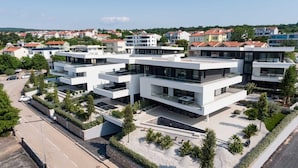 Un moderno edificio residenziale a più piani con tetto piatto, ampie finestre e un’area giardino curata.